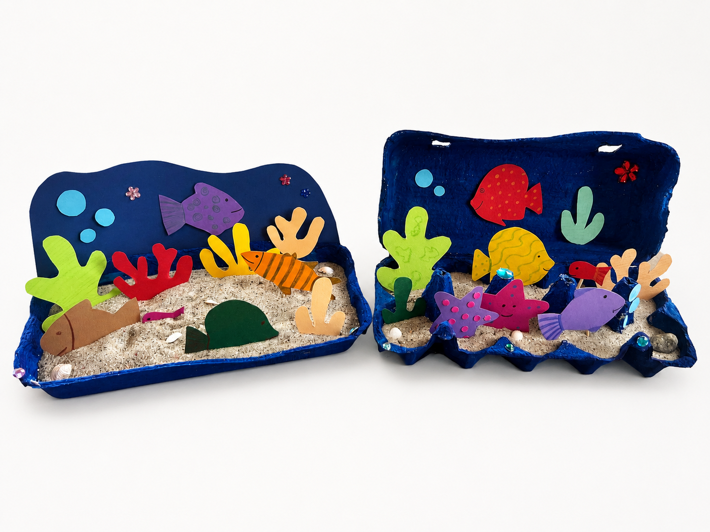 Ein kreatives Aquarium aus einem Eierkarton, bemalt und dekoriert mit bunten Papierfischen und Korallen. Perfekt für ein DIY-Projekt.