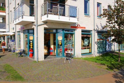 Die Inselbäckerei Börke & Sohn in Burgtiefe zeigt einen einladenden Eingang mit großen Fenstern und einem kleinen Tisch im Freien. Ein sonniger Tag.