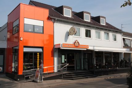 Die Inselbäckerei Börke & Sohn in der Osterstraße zeigt einen modernen, orangefarbenen Anbau neben dem traditionellen Gebäude.