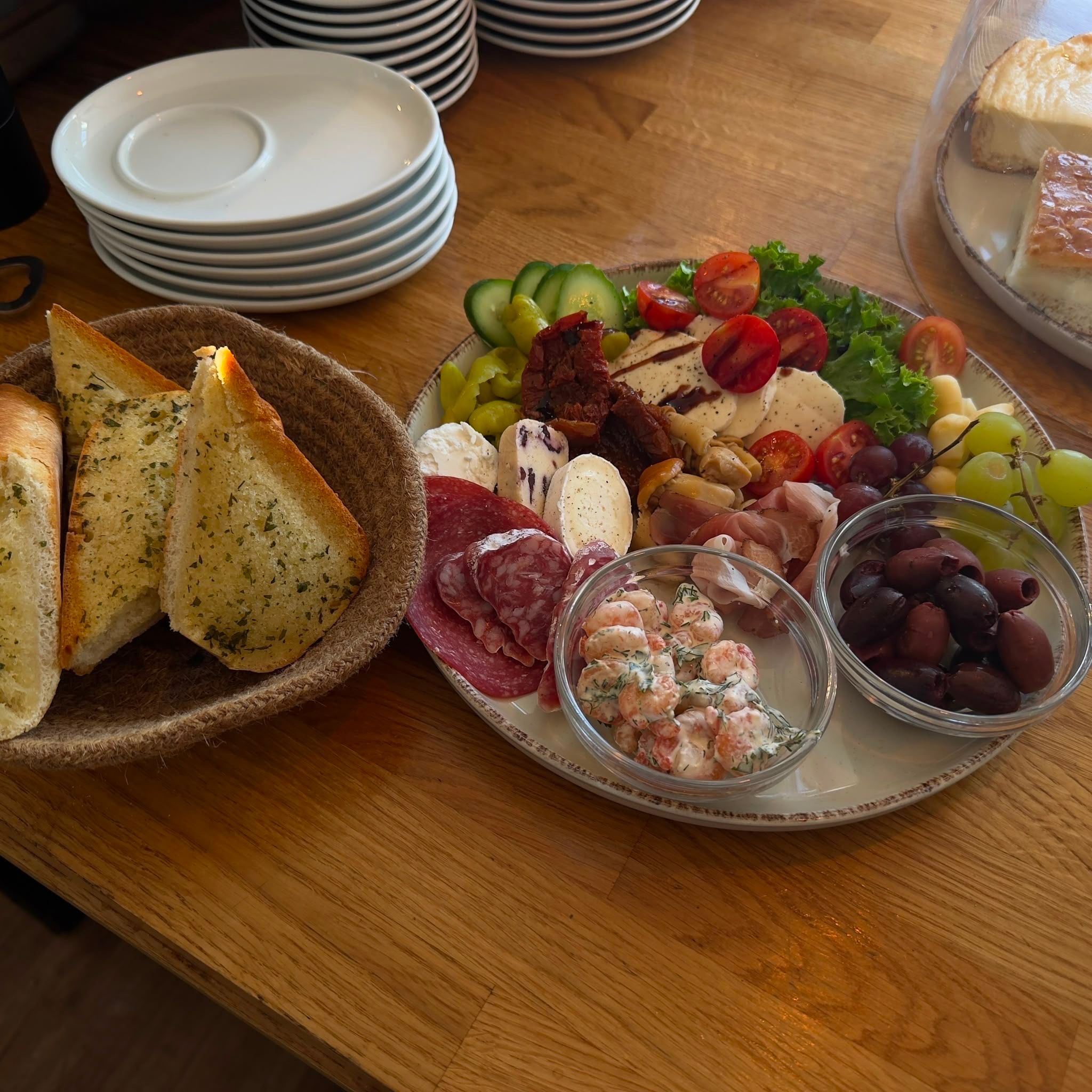 Antipasti-Platte mit Oliven, Käse, Wurst, Gemüse und Knoblauchbrot auf einem Holztisch. Perfekt für ein geselliges Beisammensein.