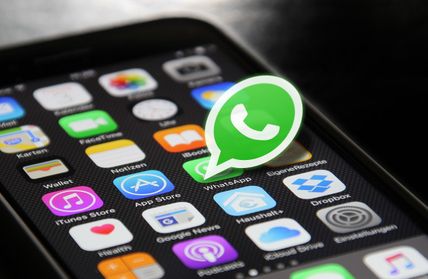 Smartphone-Bildschirm mit verschiedenen App-Symbolen, darunter das grüne WhatsApp-Symbol in der Mitte.