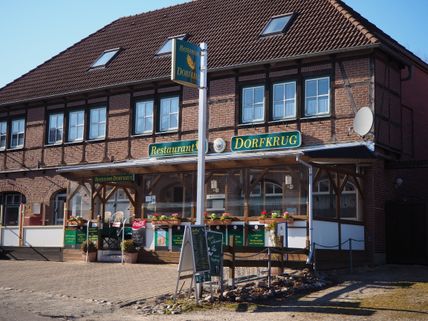 Ein traditionelles Restaurant namens 'Dorfkrug' in einem Backsteingebäude mit Holzelementen und Blumendekorationen.
