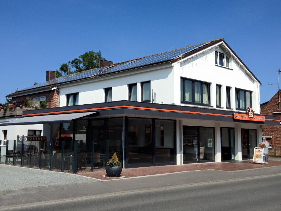 Die Inselbäckerei Börke & Sohn in Landkirchen präsentiert sich mit einer modernen Glasfassade und Solarpanelen auf dem Dach unter blauem Himmel.