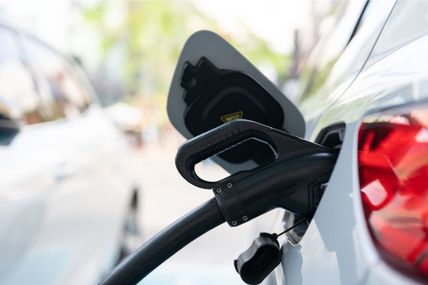 Ein Elektroauto wird an einer Ladestation geladen. Der Ladestecker ist in die Ladebuchse des Fahrzeugs eingesteckt.