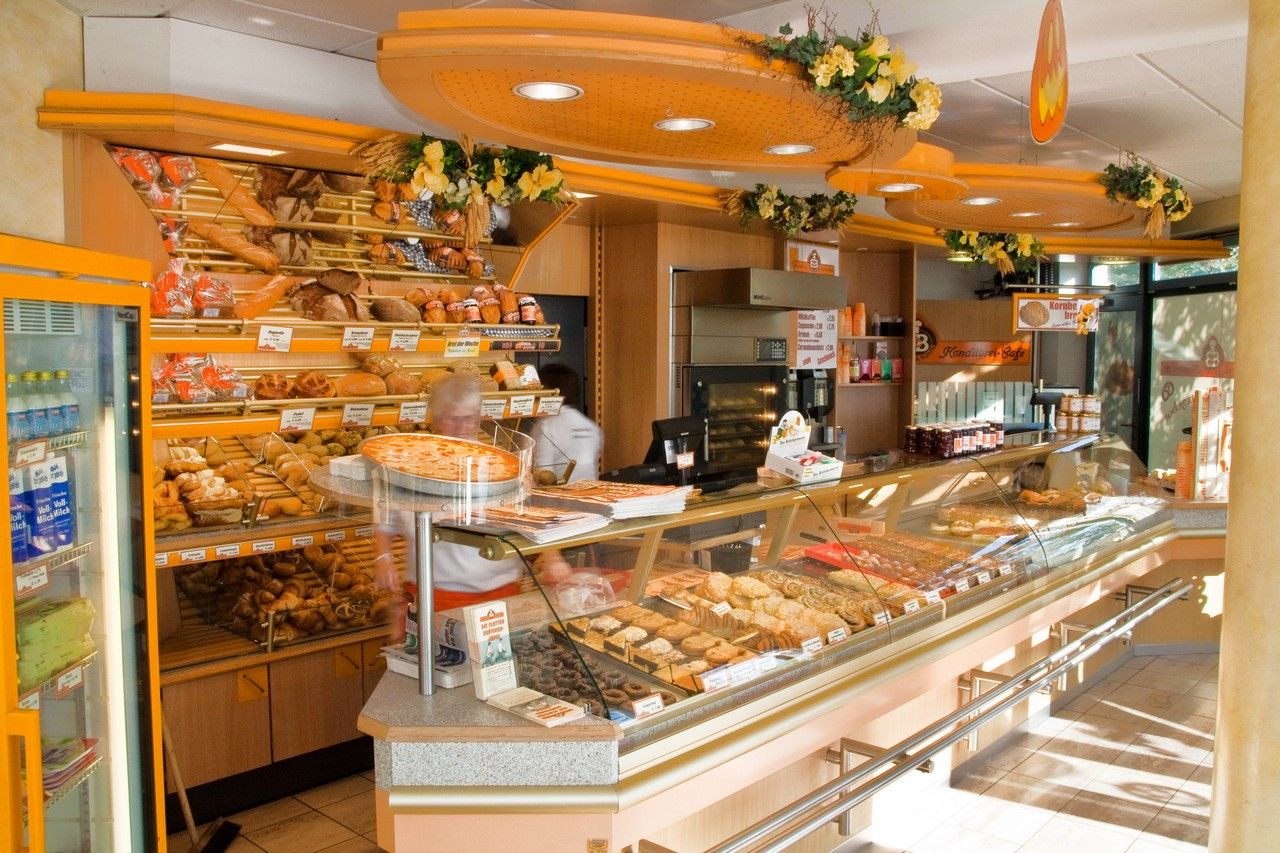 Die Inselbäckerei Börke & Sohn in Burgtiefe zeigt eine einladende Theke voller frischer Backwaren und Brote. Dekorative Blumen schmücken den Raum.