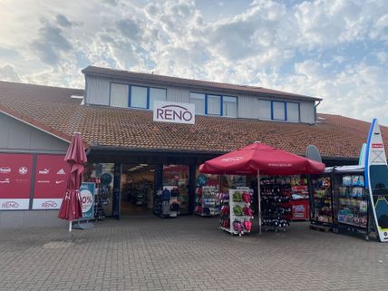 Reno-Schuhgeschäft mit roten Sonnenschirmen und Verkaufsständen im Freien. Der Himmel ist bewölkt.