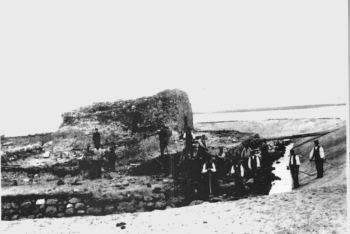 Ruine der Burgruine Glambek auf Fehmarn, umgeben von mehreren Personen in historischer Kleidung, die an der Ausgrabung arbeiten.
