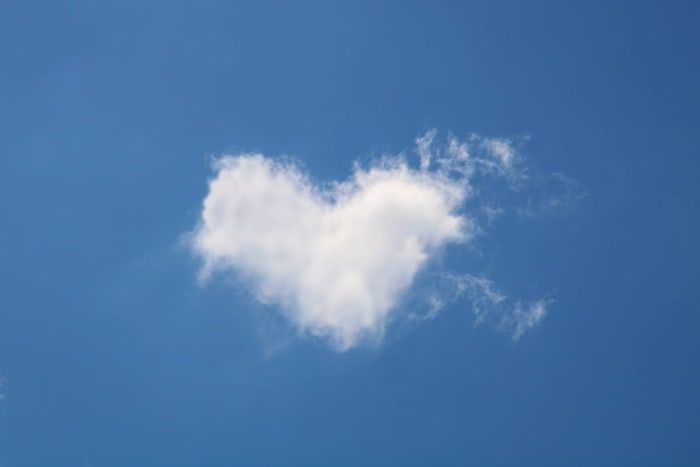 Herzförmige Wolke am blauen Himmel zum Valentinstag.