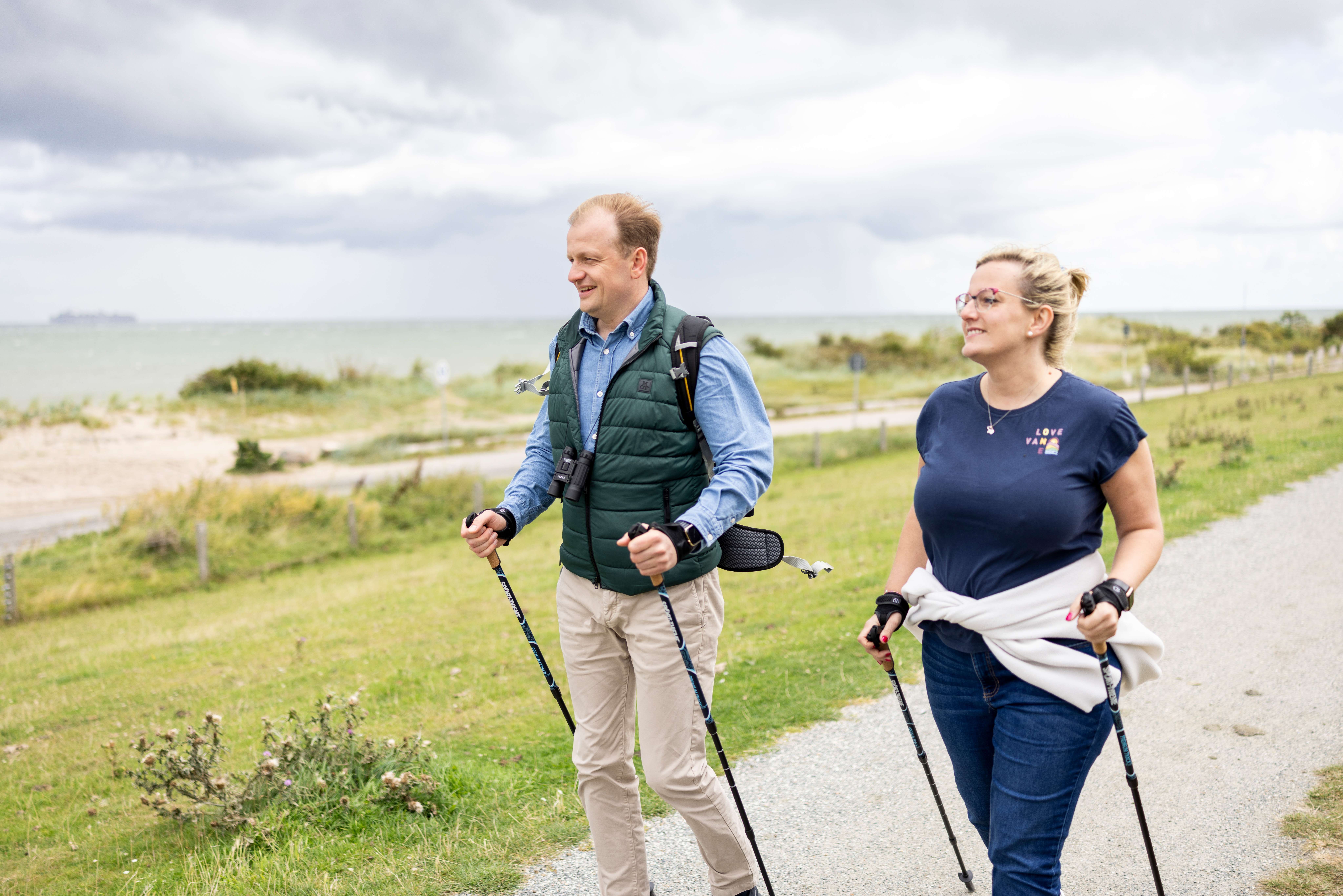 Ein Paar Wandert mit Nordic Walking Stöcken auf dem Deich in Altenteil
