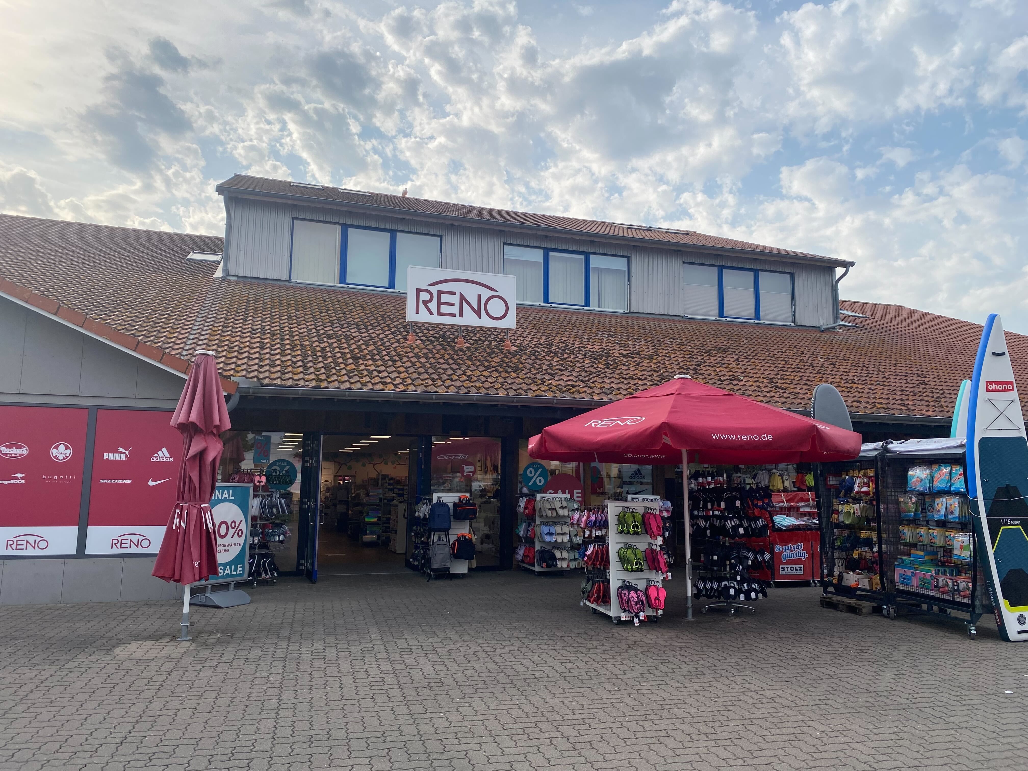 Reno-Schuhgeschäft mit roten Sonnenschirmen und Verkaufsständen im Freien. Der Himmel ist bewölkt.